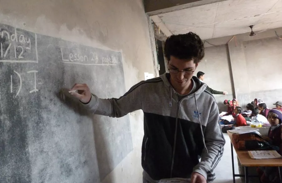 Children learning with volunteer using charts and drawings